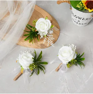 Detailed view of artificial white rose boutonniere with green leaves and ribbon for wedding.