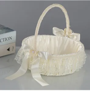 Close-up detail of ivory wedding flower basket with delicate lace trim and satin bows.