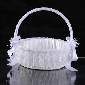 Elegant white satin wedding flower girl basket with lace ruffles and bows for ceremony.