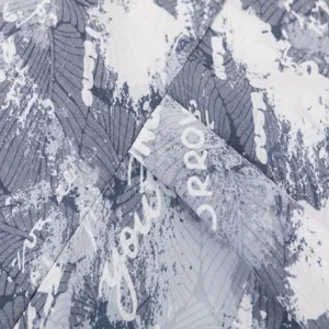 Close-up fabric detail of men's casual Hawaiian shirt featuring leaf print and stylish lettering.