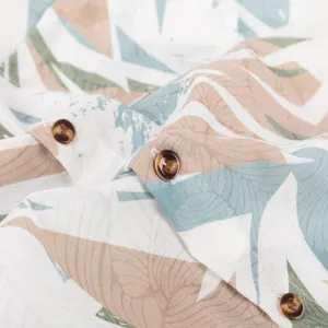 Close-up detail of men's summer short sleeve Hawaiian shirt fabric print and button.
