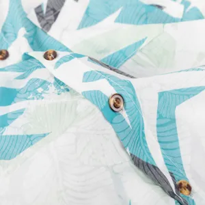 Close-up detail of mens casual tropical leaf print short sleeve lapel shirt button texture.