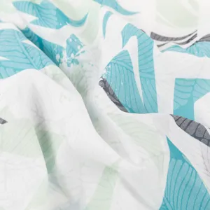 Close-up view of tropical leaf printed fabric texture for men's casual Hawaiian shirt.