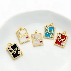 Vue detaillee de pendentifs lettre MAMA dores avec email colore et strass brillants.