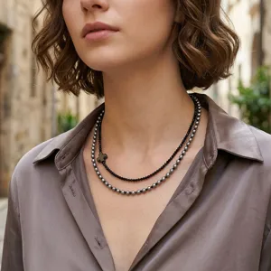 Close-up van gelaagde kraalketting met kruishanger, trendy en stijlvol sieradenontwerp.
