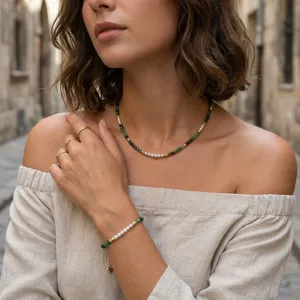 Close-up detail shot of beaded turquoise and pearl necklace and bracelet set worn by model.