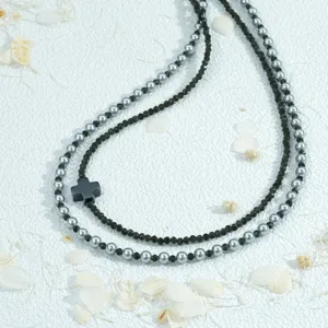 Gelaagde kralenketting met zwarte kruishanger, modieuze multi-strand sieradenaccessoire.