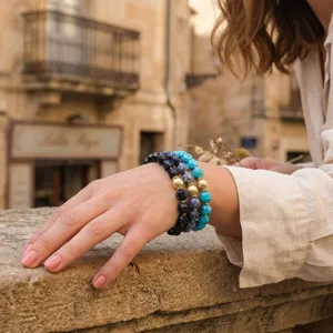 Layered gemstone beaded bracelet stack with faceted blue stones and gold accent beads style.