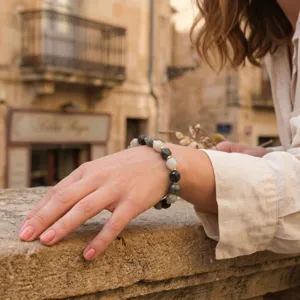 Close-up detail shot of faceted multicolor gemstone bead bracelet on wrist outdoors.