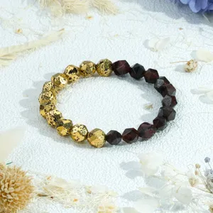 Gefacetteerde stenen elastische armband met vergulde vulkanische rots en rode kralen chic.