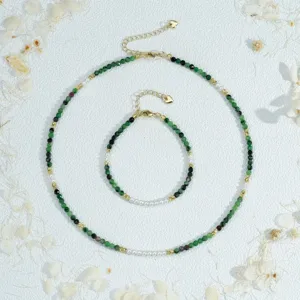 Detailed close-up of handmade beaded jewelry set featuring green stones and pearls.