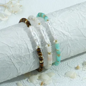 Gros plan détaillé d'un ensemble de bracelets en perles baroques et pierres sur support texturé.