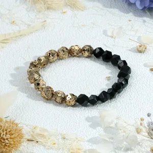 Elastische armband van gefacetteerde steen met gouden vulkanische steen en zwarte kralen.