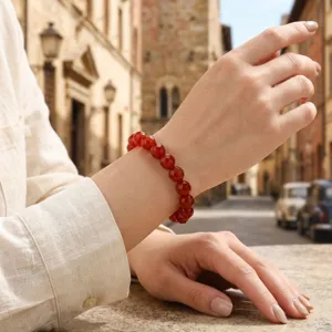 Gedetailleerde opname van een rode gefaseerde kralenarmband om de pols, elegante vintage stijl.