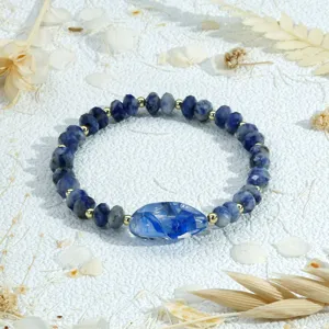 Detailopname van blauwe kristalglas kraal armband met gouden afstandhouders en middenkraal.