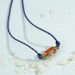 Handmade evil eye necklace featuring a colorful hexagonal prism pendant on a braided cord. Detail.