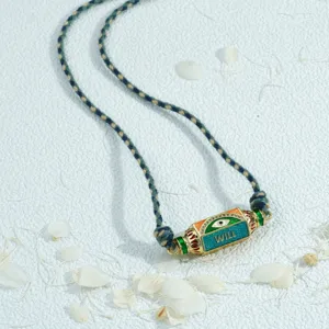 Evil eye hexagonal prism necklace pendant detail showing colorful enamel and braided cord.