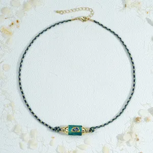 Detail shot of braided rope necklace with green enamel hex prism pendant and adjustable metal chain.