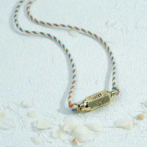 Colorful braided cord necklace with gold cylinder pendant, detailed view of fashion jewelry design.
