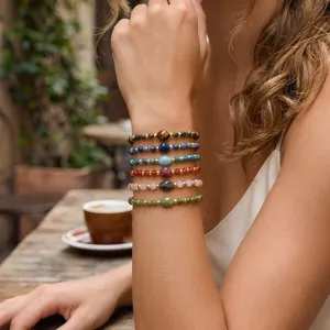 Primer plano detallado de pulseras de cuentas de piedras preciosas multicapa en la muñeca.