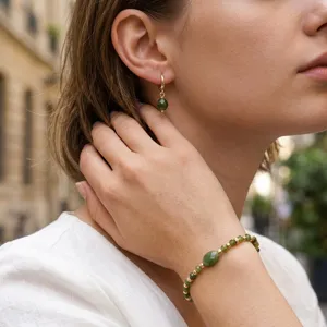 Primer plano detallado de elegante pulsera de cuentas de piedras preciosas verdes y aretes.