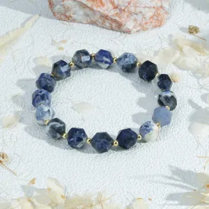 Detailfoto van gefacetteerde edelsteen armband met blauwe kralen en gouden tussenstukken.