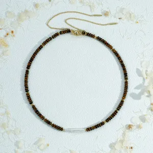 Vue détaillée du collier ras du cou en perles d'œil de tigre et perles baroques dorées.