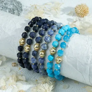 Detailed view of stacked faceted blue stone beaded bracelets with golden metal accents.