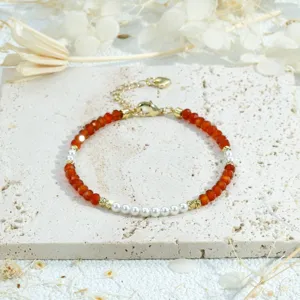 Elegant beaded bracelet featuring vibrant orange faceted beads, white pearls, and gold accents.