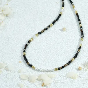 Delicate beaded necklace with faceted dark beads, gold spacers and elegant white pearls.