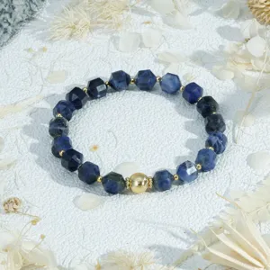 Close-up detail of a blue faceted gemstone beaded bracelet featuring a central textured gold bead.