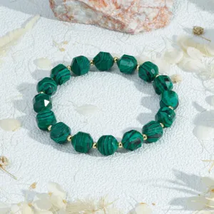 Close-up van de gefaseerde groene malachiet kralen armband met glanzende gouden afstandskralen.