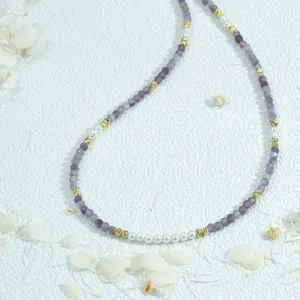 Exquisite beaded necklace detail shot featuring purple gemstone beads and pearls.