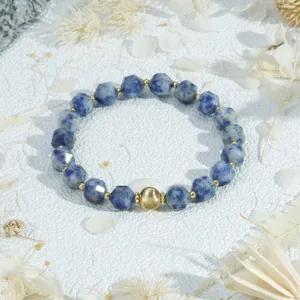 Close-up detail of blue faceted gemstone bead bracelet with gold spacer beads and centerpiece.