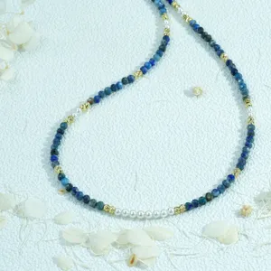 Close-up of the blue beaded necklace with pearls and gold spacers, showing fine texture.