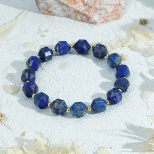 Detail van gefacetteerde lapis lazuli kralen met blauwe textuur en gouden metalen afstandshouders.