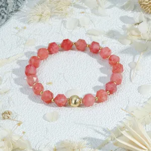 Faceted pink gemstone bead bracelet detail view featuring elegant golden metal spacers.