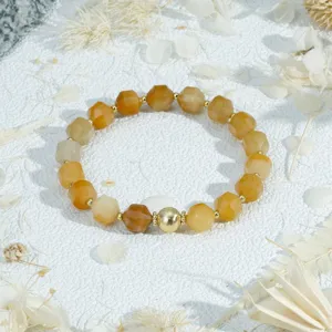 Detailed shot of the yellow faceted bead bracelet with golden metal spacers and central bead.