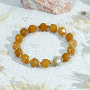 Gekorfde halfedelsteen kralen armband met gouden tussenkralen in gedetailleerde weergave.