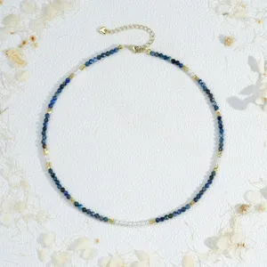 Close-up detail of blue faceted beaded necklace with faux pearls and delicate gold chain trim.