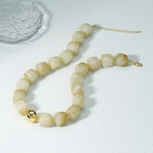 Nahaufnahme einer stylischen Acryl-Wuerfel-Perlenkette mit goldenem Kugel-Anhaenger.