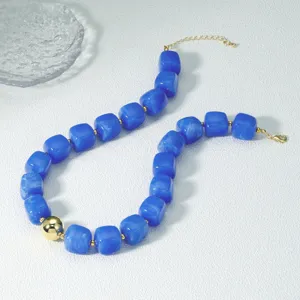 Detailansicht der blauen Acryl Perlenkette mit strukturierten quadratischen Perlen und Goldakzenten.