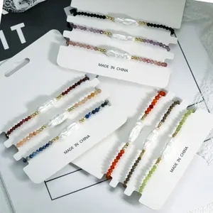 Detailopname van onregelmatige barokparel edelsteen kralen armbanden op witte kaarten.