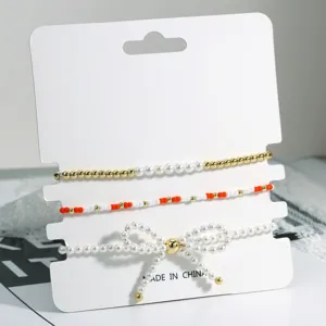 Perlenarmband Detail, Perlen Schleife Design, mehrlagiger stapelbarer Schmuck, elegantes Accessoire.