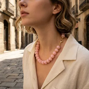 Primo piano di una elegante collana in perline rosa con distanziatori dorati, stile chic.
