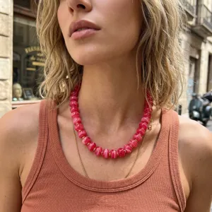 Primo piano dettagliato della collana di perle in acrilico rosa indossata dalla modella.