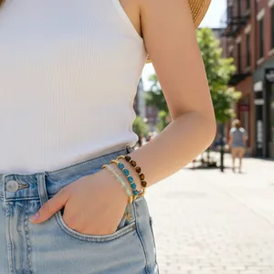 Close-up van gestapelde halfedelsteen kralenarmbanden om de pols in straatstijl.