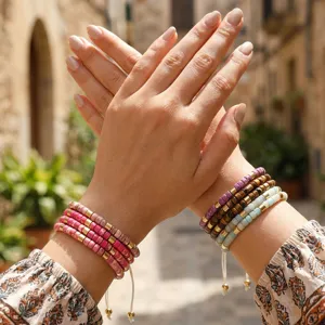 Close-up van gestapelde boho kralenarmbanden met metalen spacers en verstelbaar koord.