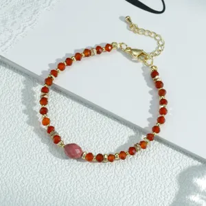 Pulsera de cuentas rojas con detalles dorados y cadena de extensión, joya elegante.