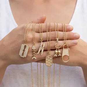 Gros plan détaillé de plusieurs colliers pendentifs en or avec cristaux zircon dans les mains.